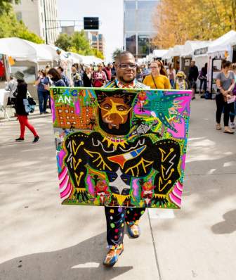 A black man walks down the center of Art Fair on the Square.