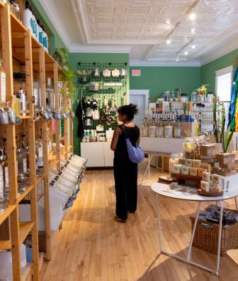 A woman stands and looks at products on a shelf at Green Life Trading Co.