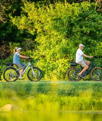 A view of two people from the side as they bike along a scenic nature route