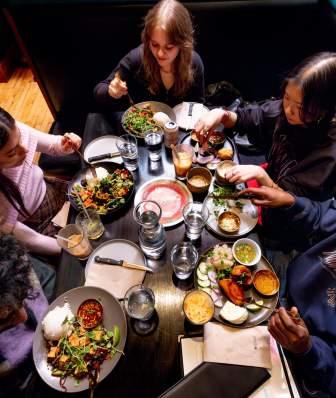 A group of five men and women gather around a table to eat Laotian food at Ahan
