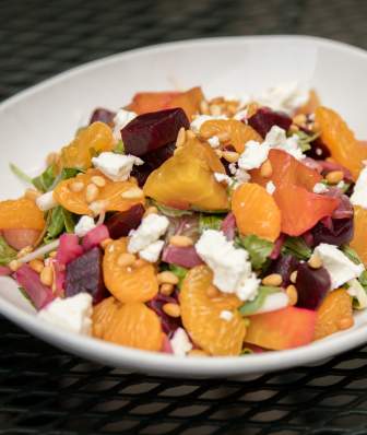 A bowl of salad with lettuce, mandarin oranges, beets, and feta cheese