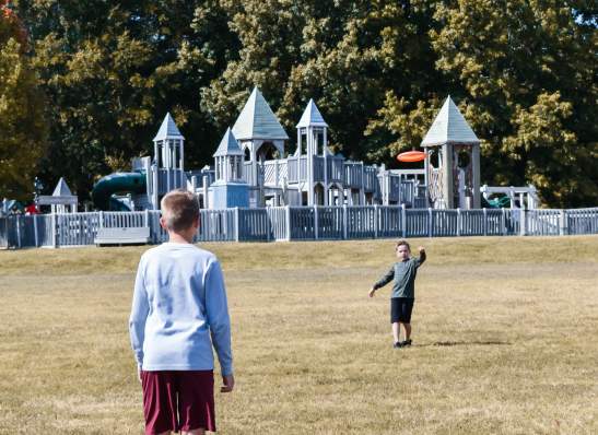 boys playing frisbee by a huge playground