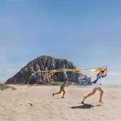 kids playing with kites on beach in front of Morro Rock