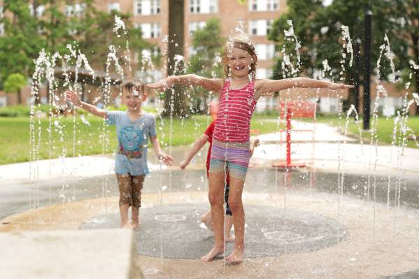 A young girl and boy play in fountains of water at the Thompson Park Splash Pad in Overland Park, KS