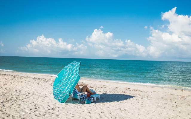 Woman relaxing on the beach under a large umbrella