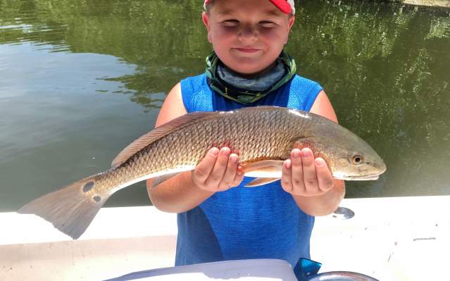 Little boy holding a freshly-caught redfish