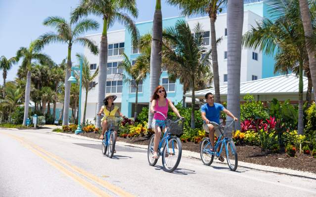 Three people riding blue bikes on Manasota Key courtesy Manasota Key Resort