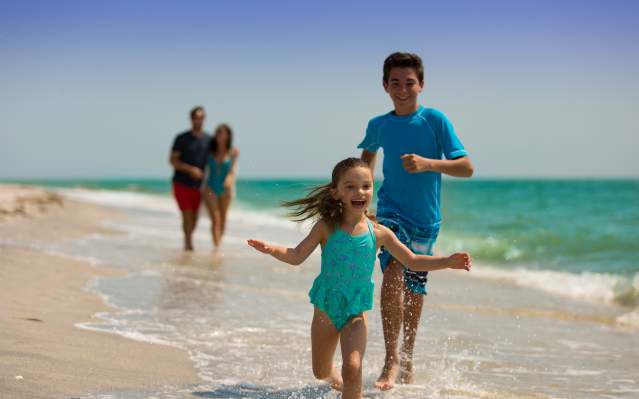 Family on beach at Palm Island Resort with little girl running joyfully