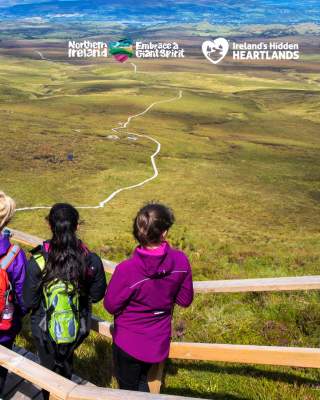 Group of walkers looking out over the landscape from the boardwalk at Cuilcagh Mountain.