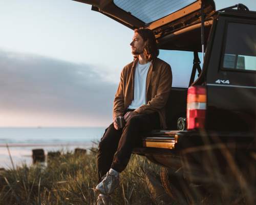 Person sat on tailgate on car next to the beach in East Yorkshire