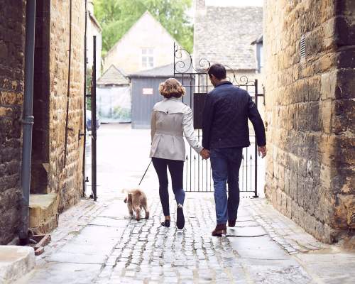A couple walking a dog outside the Lygon Arms Hotel