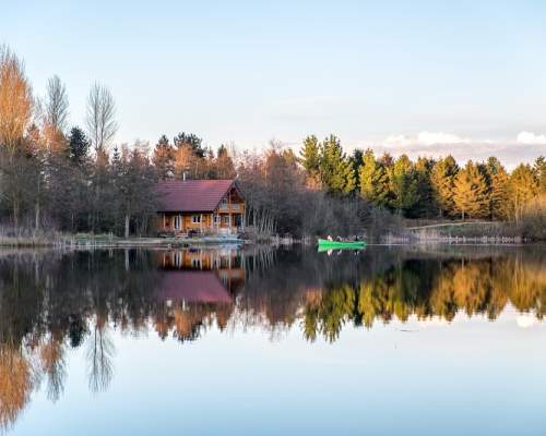 A cabin looks over a lake on a bright winter day at Log House Holidays
