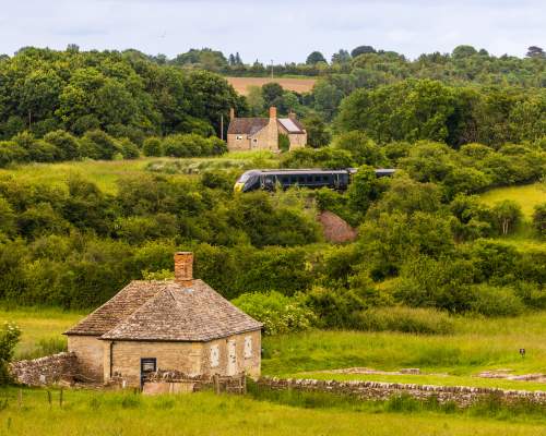 A view of North Leigh Roman Villa with a GWR train passing in the distance behind