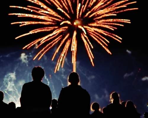 a group of people sit outside and watch a firework display in Devon