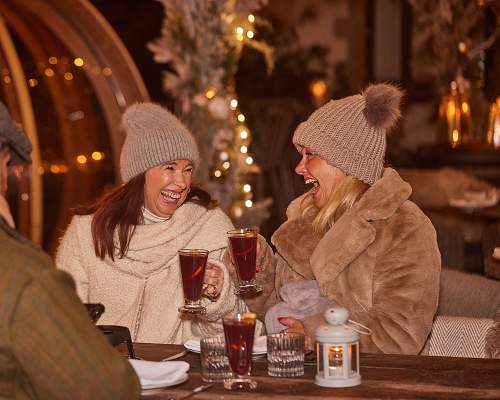 Two ladies in bobble hats enjoying mulled wine at a Christmas market at Wild Thyme and Honey