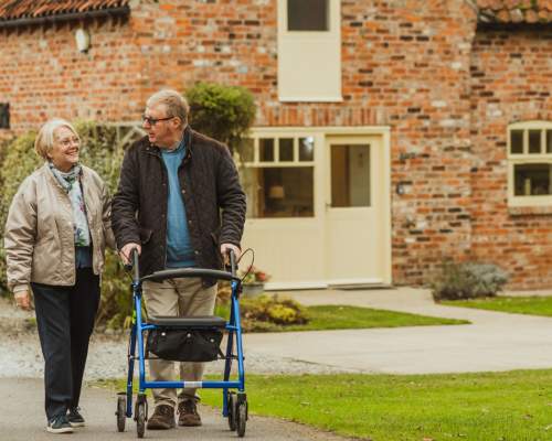 A couple walking the grounds at Broadgate Farm Cottages in East Yorkshire. The man is walking with the aid of a rollator.