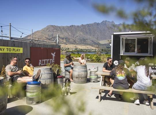 People sitting in the outdoor beer garden at Altitude Brewing with the Remarkables mountains in the background