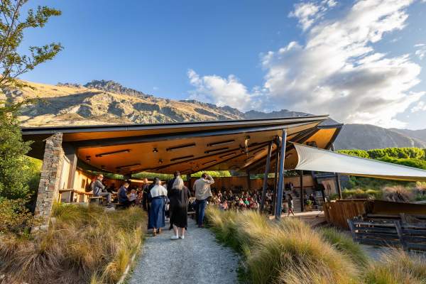 A group of people gather at an outdoor venue surrounded by mountains and trees