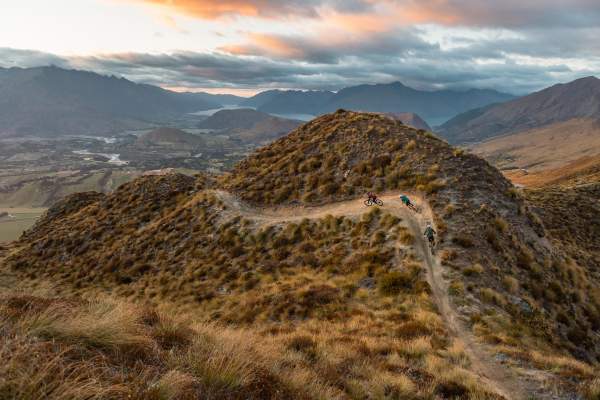 Mountain bikers riding at the top of a mountain with views of the basin in the background