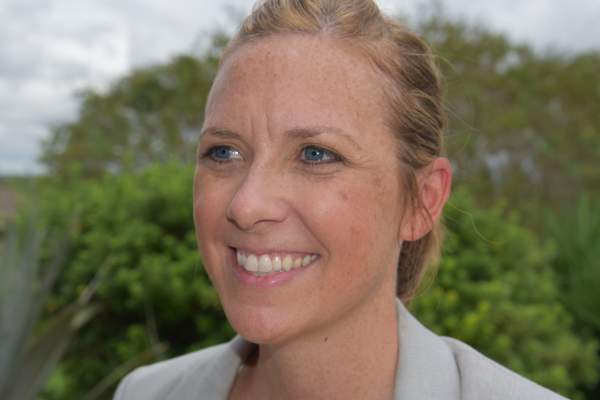 Dr. Kiersten Stanzel smiles to the side of the camera in front of a green, outdoors background.