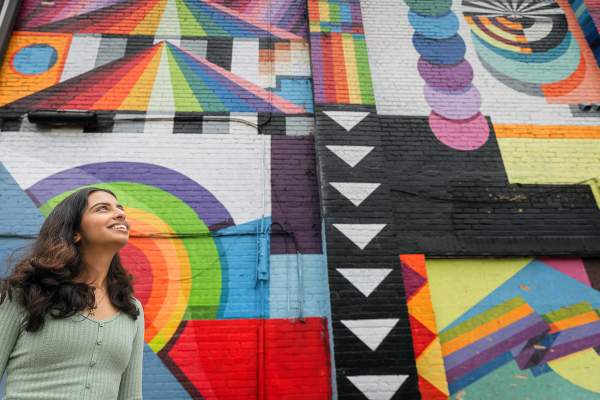 Woman with long hair looking up at brightly covered mural on side of building