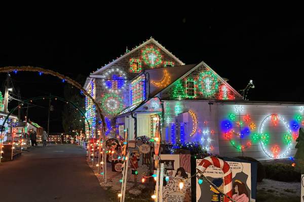 House at Koziar's Christmas Village lit up with Christmas lights with a snowman in the front