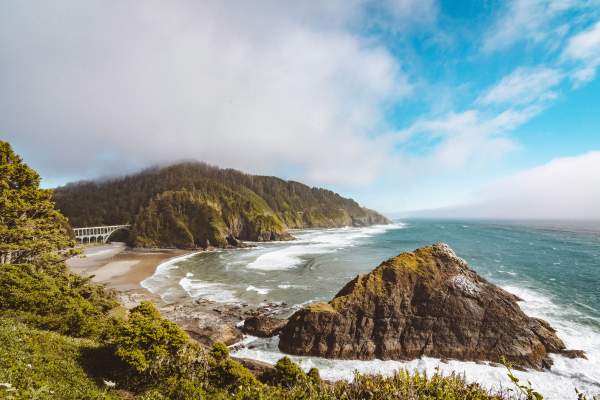 Viewpoint from Heceta Head Lighthouse showing rocky coastline and a large bridge.