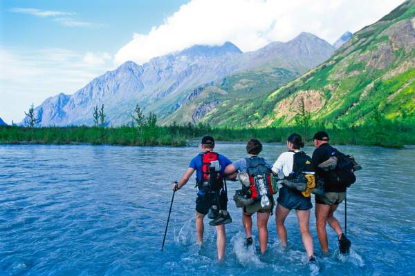 A group of hikers cross Eagle River while hiking the Crow Pass in the Chugach Mountains.