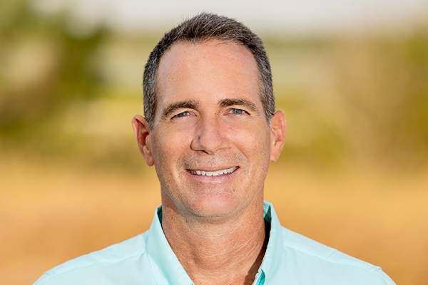 Headshot of a man in a light teal shirt that says Harte Research Institute