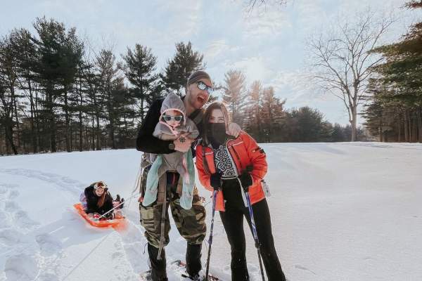 Mom and dad, with two kids, skiing and sledding in the snow