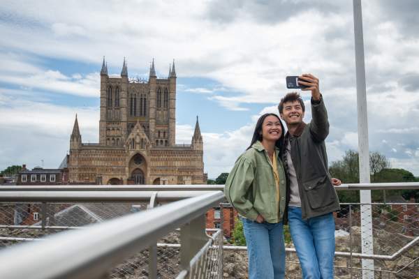 Two people having a selfie in front of Lincoln Cathedral from the walls of the castle