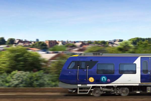 Northern Rail train on tracks with greenery in the background