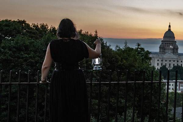 Woman holding a lantern looking at the state house during a Providence Ghost Tour