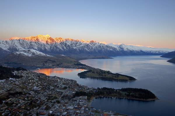 Aerial shot of Queenstown with snow capped mountains, lake and town