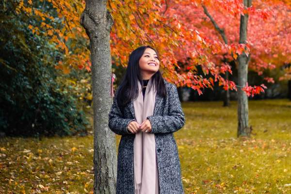 Woman in coat and scarf walking in a fall scene