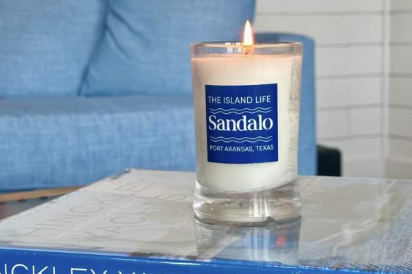 Vida Caña Rum candle sitting on blue coffee table books in a bright coastal-style room.