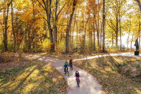 Family bikes on the B2B trail during fall on a dirt pathway with treelined background