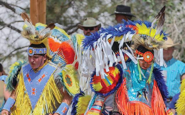 Two Native American dancers in full regalia perform in the Indian Village