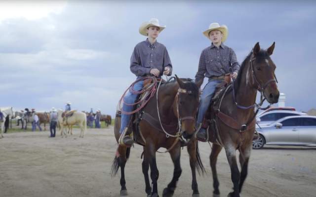 Two young cowboys ride their horses while talking in Cheyenne, Wyoming