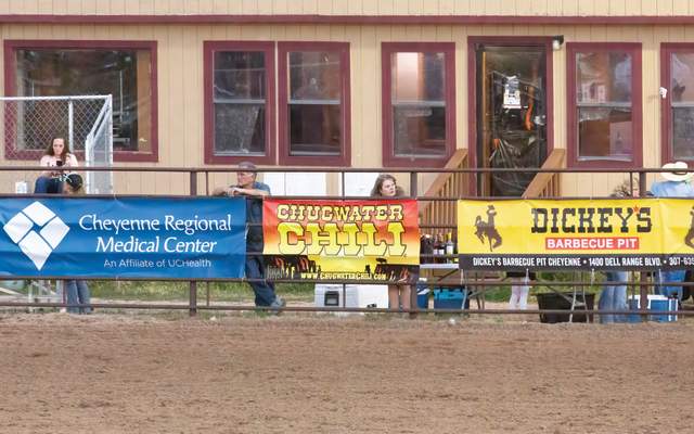 Banners hang on a fence at the hell on wheels rodeo