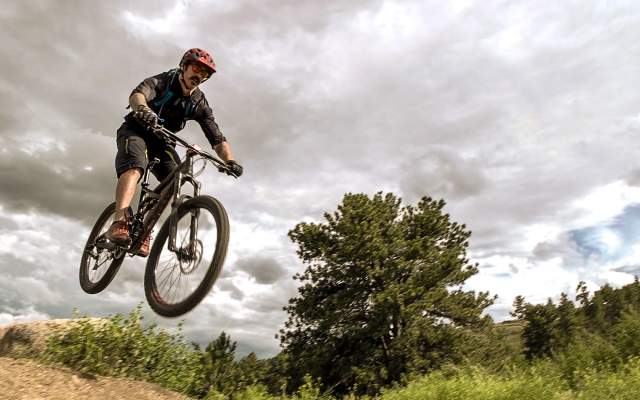 Man on mountain bike catches air in front of a cloudy sky outside Cheyenne, Wyoming