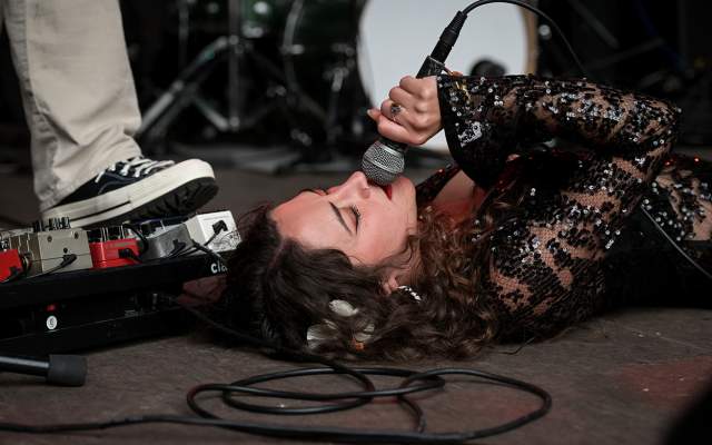 A woman lying on the ground singing into a microphone