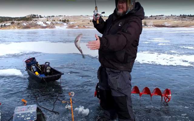 A man ice fishing at Curt Gowdy brings in his catch