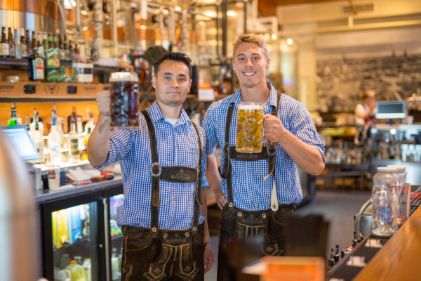 Two men in lederhosen holding liter steins of beer at the Bavarian Bierhaus