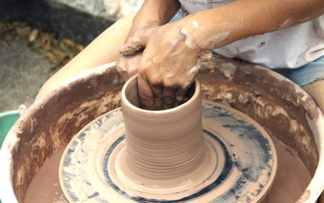 Hands shaping clay on a pottery wheel during an arts and crafts workshop in Fayetteville, NC.