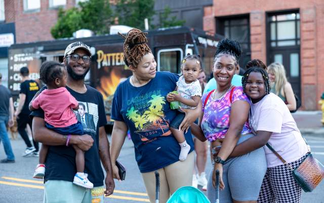 African-American family with three children, parents, and grandmother smiling at local festival
