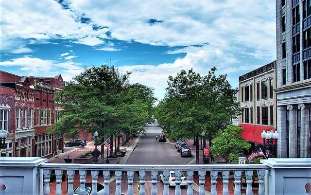 Downtown Fayetteville street lined with trees and historic buildings under a cloudy sky