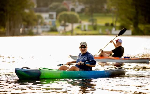 People kayaking on Hope Mills Lake, enjoying outdoor recreation on a sunny day.