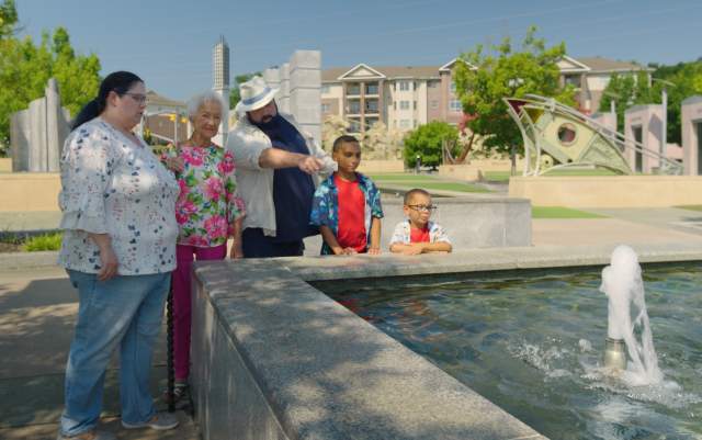 Multi-generational family gathered around the reflection pool in Fayetteville's Veterans' Park