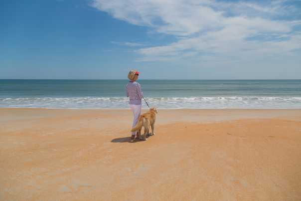 A woman walks her dog on the warm cinnamon-color sand of Flagler Beach.